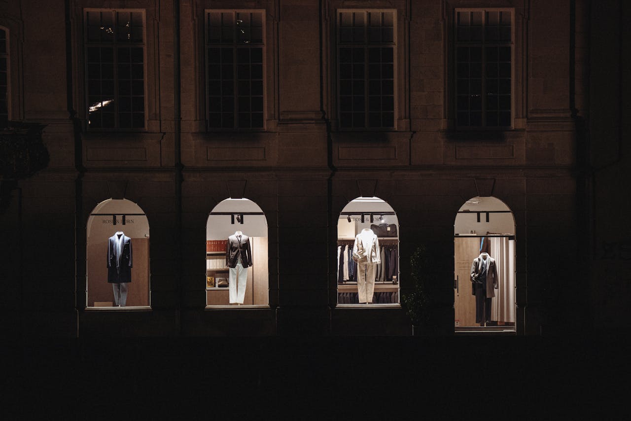 gallery-6 Stylish clothing displays visible through urban building windows at night, highlighting luxury fashion.
