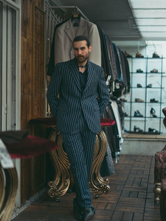 gallery-3 Man in a sleek pinstripe suit poses stylishly in a fashion boutique.